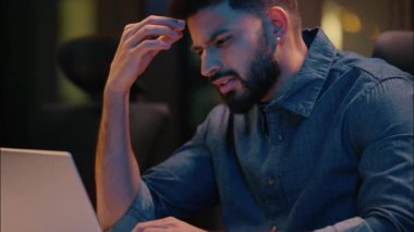 Yorgun Hintli adam iş adamı dizüstü bilgisayarda fazla mesai yapan gece vardiyasında çalışan yorgun erkek programcı sinirli erkek çalışanı baş ağrısı sorunu aşırı çalışma