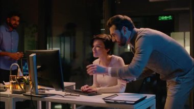 Çok ırklı takım iş arkadaşları Kafkasyalı Hintli erkek iş adamları kadın işadamları gece ofiste çeşitli iş arkadaşları bilgisayar projesini tartışıyorlar bilişim şirketinde çalışanlara yardım ediyorlar.