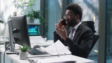 Kafası karışmış Afrikalı Amerikalı bir adamın cep telefonu işadamı cep telefonu iş telefonu görünen bilgisayar monitörü, bilgisayar çalışanı yönetici sorun sorunu, ofis müşterisine danışmanlık yapan kafası karışık bir adam.