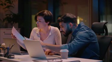 Hintli iş adamı Kafkasyalı iş ortağı iş ortağı erkek kadın dizüstü bilgisayar okuyor hayal kırıklığına uğramış çok ırklı meslektaşlar gece ofisindeki evrak sorununu vurguladılar