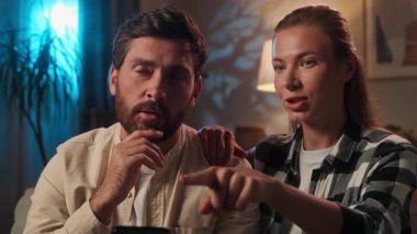 Akşamları Kafkasyalı bir çift cep telefonu kullanıyor. Eşi kanepede oturan bir kadın. İnternetten ev ürünleri alışverişini tartışıyor.