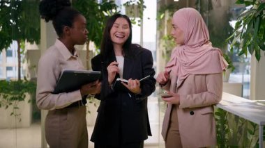 Ofisteki üç çok ırklı iş kadını, Afrikalı Müslüman Asyalı iş arkadaşları, iş arkadaşları, iş arkadaşları, gülümseyen kızlar, çeşitlilik, takım çalışması, tartışma, kurumsal telefon görüşmeleri.