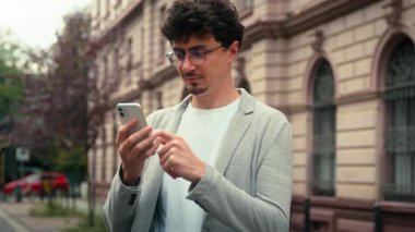 Ciddi yoğunlaşmış Hintli iş adamı şehirde cep telefonu kullanıyor. Sohbet mesajları yazıyor. Akıllı telefon uygulaması, internet, iş adamı.