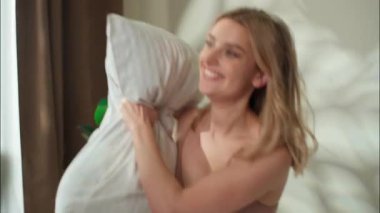 Neşeli Kafkasyalı çift yatak odasında yastık kavgası yapıyor. Aşk kadını kız arkadaş, evlilik ilişkisi partnerleri gülüyor erkek arkadaş, oyun yatağında eğleniyor.