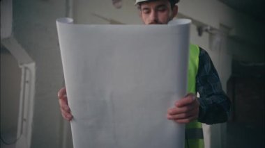 Kafkasyalı adam müteahhit inşaat mühendisinin planlarını ortaya çıkarıyor ciddi bir mimar kağıt taslağı çiziyor erkek işçi sanayi işçisi tesisatçı inşaatı projesini denetliyor