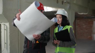 İki farklı Kafkasyalı Japon müteahhit erkek inşaat mühendisi kadın inşaat mühendisi mimar, miğfer üniformalı işçiler planlama projesini tartışıyorlar.
