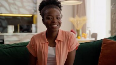 Neşeli, mutlu, mutlu, Afro-Amerikan iş kadını, etnik bayan, iş kadını, gülümseyen ev sahibi, model bir müşteri, geniş dişli, sağlıklı gülümseyen bir kameraya bakıyor.