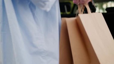 Bilinmeyen Kafkasyalı büyükanne yaşlı kadın olgun alışverişçi müşteri müşteri araba şoförü alışveriş çantalarını otomobil bagajı teslimatı siparişiyle teslim ediyor.