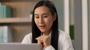 Pozitif Asyalı Japon kız ofis çalışanı insan kaynakları müdürü iş kadını neşeli Koreli kadın iş kadını çevrimiçi video görüşmesi bilgisayar araması laptopuyla iş görüşmesi.