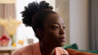 İlgilenen Afro-Amerikan iş kadını ev sahibi kadın iş kadını model kız televizyon dizisi, film komedi programı, kanepe, ev sahibi oturma odasında oturuyor.