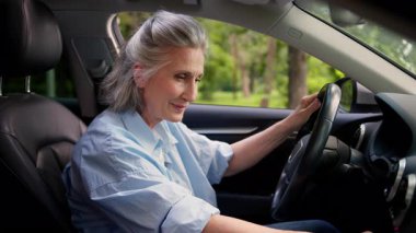 Gülümseyen Kafkasyalı olgun yaşlı kadın kıdemli büyükanne kadın araba sürücüsü araba kiralama hizmetleri müşterisi modern araçta ses sistemi panelini açın müzik dinlemenin tadını çıkarın.