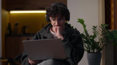 Ev adamı serbest programcısının bilgisayarında çalışan konsantre beyaz adam kulaklıkla web sitesi tasarımcısı ile sohbet ediyor sanal oyun oynayan bilgisayar erkeği kullanarak internet uygulama hipster geliştiricisi yazıyor.