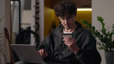 Neşeli Kafkasyalı adam ev kullanıcısında online kredi kartı laptopunu ödüyor sigorta web bankası başvurusu yapıyor hipster tüketicisi erkek siparişi alıyor bilgisayar e-ticaret interneti kullanarak.