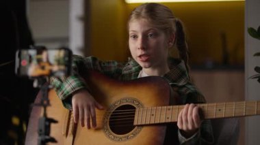 Yaratıcı Kafkasyalı küçük kız çocuğu çocuk nüfuzlu blogcu okul kızı gitar çalmayı öğretiyor şarkı söylemeyi öğretiyor online özel ders blogu video video blogu cep telefonu evde kameralı tripodla konuşuyor