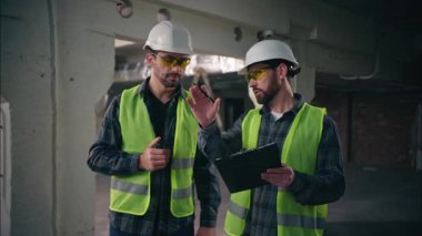İki Kafkasyalı ustabaşı inşaat teknisyenlerinde endüstriyel işleri kontrol ediyorlar mimarlar iş birliği yapıyor güvenlik üniformalı tamirciler mühendisler hakkında konuşuyor telsiz planları yapıyorlar.