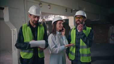 İyi ki beyaz takım arkadaşları inşaat işindeki endüstriyel projeleri denetliyor cep telefonu geliştiriyor müfettişler iş birliği yapıyor not defterleri tutan işçiler takım çalışmasını konuşuyor.