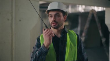 Profesyonel Kafkasyalı müteahhit telsizle konuşuyor. İnşaat işçisi ustabaşı elinde teknoloji mühendisi müfettişi. Telsiz seti, erkek denetleyici denetimi.