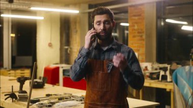 Profesyonel Kafkasyalı marangoz atölyede cep telefonuyla konuşan işçi ahşap ustası telefon bağlantısı ağı kuran müşteri marangozluğu kullanarak mimar erkekle iletişim kuruyor.