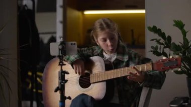 Kafkasyalı küçük kız gitar çalmayı öğreniyor çevrimiçi cep telefonu öğrencisine bakıyor yetenekli çocuk şarkısı öğreniyor müzik dersi öğreniyor akıllı telefon kameralı tripod öğretmeni video çağrısı yapıyor