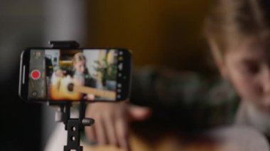 Tripod telefonundaki kamera gitar çalan küçük bir kızı kaydediyor. Kafkasyalı ergen çocuk konseri, çocuk nüfuzlu blogcu müzik videosu çekiyor. Evde gitarist akıllı telefon müzisyeni şarkı söylüyor.