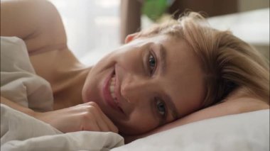 Pozitif beyaz kadın yatak odasında uyur gündoğumu gündoğumu sabah uyanıp rahatlar neşeli kadın gülümseme dişçi sağlıklı kadın rahat bir yatak odasında uzanıyor