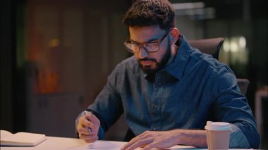 Hintli etnik adam işadamı evrak okuyor. İşveren müdürü, yatırımcı avukat. Gece vardiyasında mesai kağıtları yazan anlaşma imzaladı.