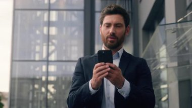 İşadamı erkek işadamı cep telefonu kullanıyor. Şehir işvereni yetişkin girişimci dışarıda yürüyor. Ofis çalışanlarının yanında yürüyor.