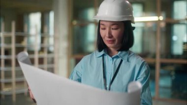 İnşaat planına bakan Asyalı inşaat mühendisi kadın müfettiş. İnşaat kağıdı taslağı. Elektriği Çinli Japon kadın müteahhit mimar.
