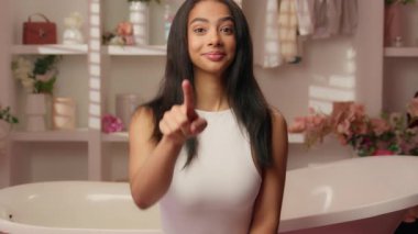 Latin Amerikalı kadın etnik kız pembe şeker banyosunu işaret ediyor. Hey sen gülümseyen İspanyol kadını işaret ediyorsun. Gülümseyen ergen başparmağını kaldırıyorsun.