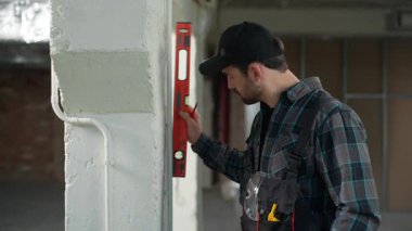 İnşaatçı mimar duvar onarımcısı apartman onarım aletlerini teftiş ediyor Kafkasyalı erkek mühendis ustabaşı müfettiş ölçü göstergesi yazıyor