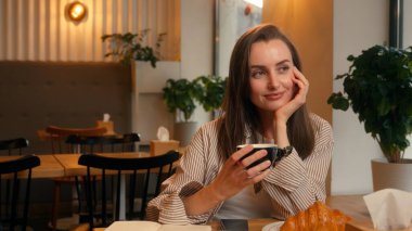 Genç, mutlu, gülümseyen, ilham veren iş kadını kadın iş kadını. Kafede çalışmak, not defterine notlar yazmak, kahve içmek, günlük tutmak. Yaratıcı süreç yazmak.