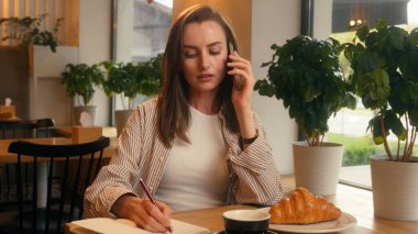 İş kadını, kafe masasında telefon görüşmesi şirket iş görüşmeleri danışman bayan iş kadını, akıllı telefon yazma notları ile müşteriyle konuş ağ yazma, bilgi yazma görevi planlama.