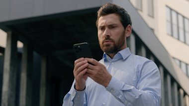 Kafkasya 'da telefon kullanan ciddi bir işadamı orta yaşlı bir iş adamı cep telefonuyla sohbet eden bir girişimci açık havada cep telefonu tutuyor sosyal medya teknolojisinin çevrimiçi çalıştığını düşünüyor.