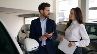 Otomobil galerisinde konuşan iki kişi, beyaz erkek müşteri müşteri işadamı, kadın satıcı otomobil tüccarı işadamıyla yeni lüks otomobil konuşmalarını seçiyor.