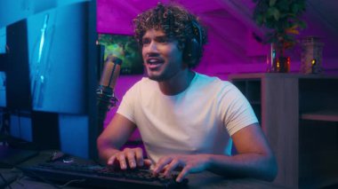 Müslüman, Arap, Hintli, oyuncu, erkek, oyun oynuyor. İyi sonuç, siber spor, bilgisayar, zafer blogu, video blogu, oyuncu heyecanlı flamalı radyo sunucusu. Başarı çığlığı, mikrofon.