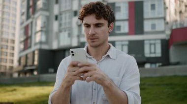 Kafası karışmış Kafkasyalı adam elinde cep telefonu, akıllı telefon, hata, hata, uygulama, bağlantı, internet, sohbet elemanı, üzgün iş adamı dışarıda hayal kırıklığına uğramış durumda.