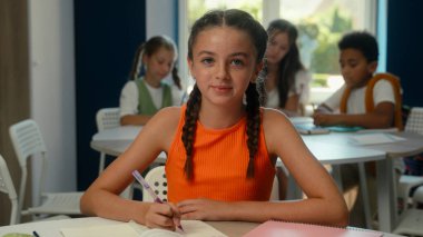 Masa başında okuyan beyaz kız öğrenci öğrenci. Gülümseyen liseli kız. Yazma dersi öğreniyor.