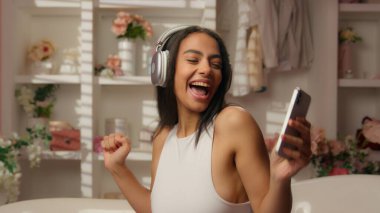Latin Latin kız mutlu, neşeli, kaygısız kadın pembe şeker banyolarında müzik dinliyor, kulaklıklı, genç bayan rahat dans ediyor, müzik dinliyor, müzik dinliyor, müzik dinliyor, kendine özen gösteriyorlar.