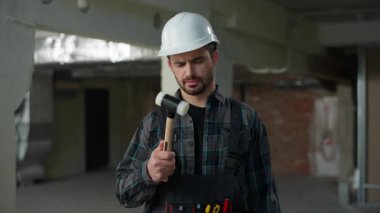 İnsan müteahhitinin elinde çekiç, beyaz erkek mimar, inşaat alanında ustabaşı, inşaat işçisi, mimar, inşaat ustası sabit şapka güvenliğiyle ilgilenen kameraman kafası karışmış.