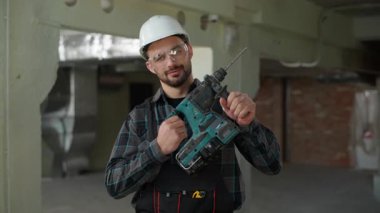 Yakışıklı inşaat mühendisi ustabaşı inşaat alanının onarımı için döner sondaj çalışması yapıyor Kafkasyalı İspanyol adam erkek, endüstriyel işçi sondaj aleti delicisi.