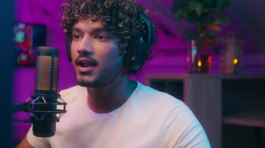 Arap Hintli Müslüman adam mikrofon mikrofonu ile konuşan erkek sunucu blogcu blogcu, blogcu oyuncu vlogger çevrimiçi oyun akışı radyo sunucusu etkileyicisi bağımlılığı neon ev
