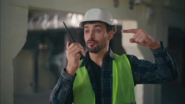 Kafkasyalı müteahhit telsizdeki telsizciyi işaret ediyor. İnşaatçı müteahhit erkek. Telsiz seti, teknik bağlantı mühendisi.
