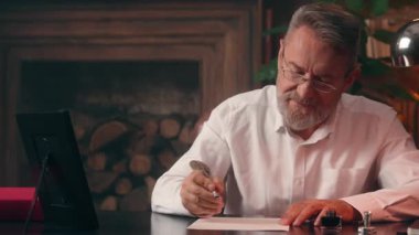 Yaşlı beyaz adam kağıt döküman yazıyor. Erkek iş yeri başvurusu. Kapalı alanda olgun kıdemli profesör lider iş adamı.