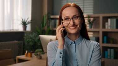 Gülümseyen kaygısız iş kadını cep telefonu konuşan Kafkasyalı kadın çalışan akıllı telefon konuşmaları iş kadını ofis müdürü iş yerinde cep telefonuyla konuşma