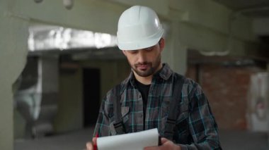 İnşaat mühendisi inşaat alanının onarım sorununu araştırıyor. Ustabaşının yazma planı hoşnutsuz. İspanyol erkek teknisyen.