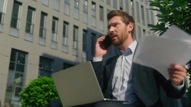 Stresli iş adamı cep telefonunu tartışıyor dizüstü bilgisayarını arıyor kağıt dökümanlarını çöpe atıyor Kafkasyalı kızgın erkek işadamı 40 'lı yaşlarda işveren orta yaşlı girişimci hata diye bağırıyor.