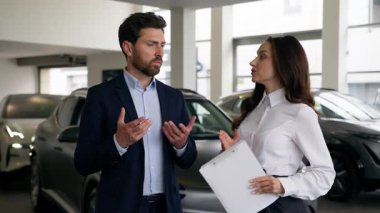 İki kişi araba kuaföründe işadamı müşterisi satış görevlisi kadın otomobil galerisi ile konuşuyor.