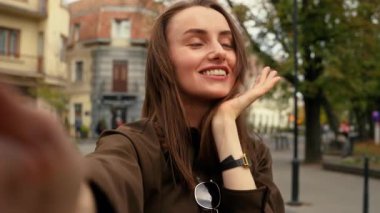 Mobil telefon kamerası görüntüsü gülümseyen beyaz kadın gülümsüyor. Kentteki sokak kızı elinde akıllı telefon görüntüsü, video bloğunda canlı yayın yapan video görüntüsü tutuyor.