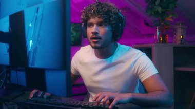 Konsantre olmuş mutlu Arap Hintli Müslüman adam klavye bilgisayar oyunları yazarken video oyunu siber sporu yaparken heyecanlı erkek oyuncu flaması kazanırken çevrimiçi oyuncu kazanırken iyi eğlenceler.