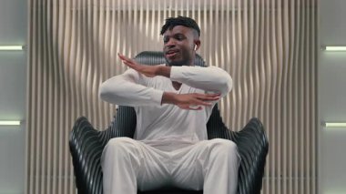 Afrika kökenli Amerikalı erkek, kulaklıkla müzik dinliyor, dans ediyor, kablosuz kulaklıkla şarkı dinliyor fütüristik beyaz stüdyoda fütürizm yenilikçiliğinden keyif alıyor.